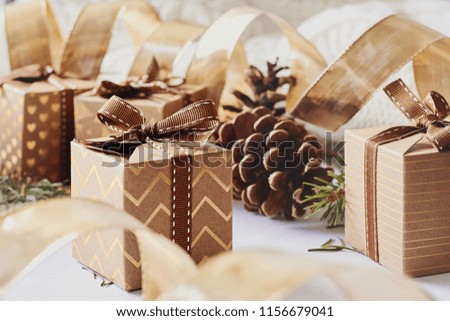 Christmas and New Year holidays concept. Gift boxes with ribbon, fir branch, cones on white knitted background. Side view, selective focus