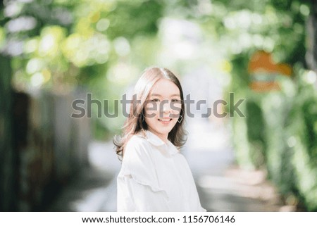 portrait of asian girl with white shirt and skirt looking smile in outdoor nature vintage film style