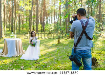 Photographer taking Pictures of the Bride in the summer forest