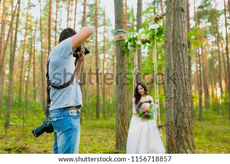 Photographer taking pictures of the bride on a rope swing with rustic style bridal bouquet