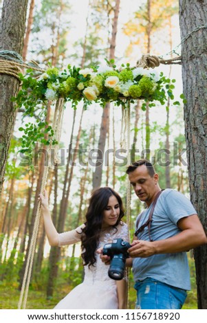 Photographer taking pictures of the bride on a rope swing and watching recently taken photos
