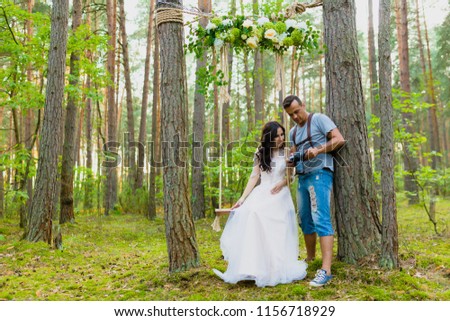Photographer taking pictures of the bride on a rope swing and watching recently taken photos