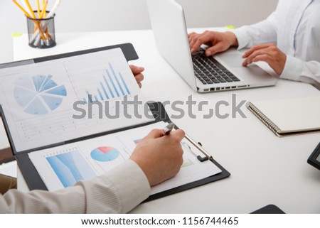 Business team two colleagues discussing new plan financial graph data on office table with laptop and calculator