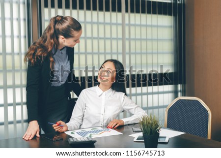 Women looking financial documents in laptop at table