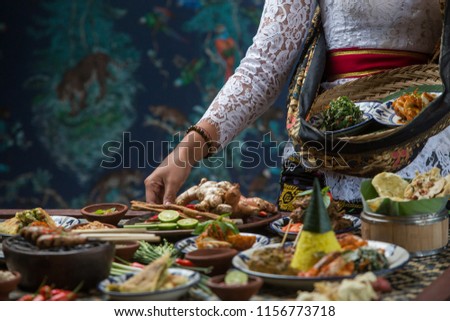 Indonesian cuisine - Many traditional Balinese dishes on the table. Waitress is serving food Royalty-Free Stock Photo #1156773718
