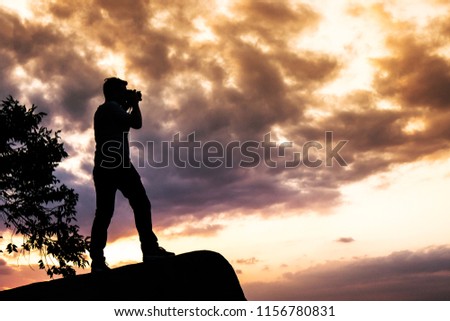 Silhouette Man taking photo of beautiful cloundy sunset