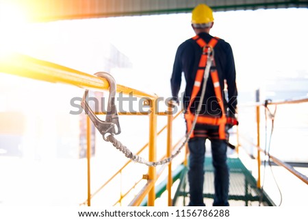 Construction worker use safety harness and safety line working on a new construction site project. Royalty-Free Stock Photo #1156786288