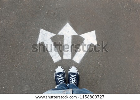 Woman standing near arrows on asphalt, top view. Choice concept Royalty-Free Stock Photo #1156800727