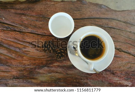 Picture from top of black coffee in white glass, placed on wooden table with hot tea in morning cafe.
