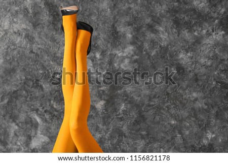 Legs of beautiful young woman in color tights on dark textured background