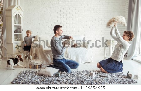 happy family and pet dog playing with pillows in spacious living room