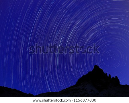 Long exposure image showing Night sky star trails over mountains
