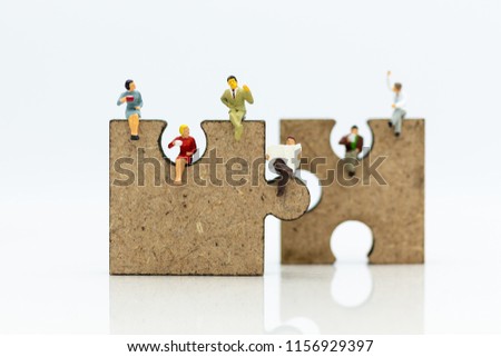 Miniature people : businessman sitting on jigsaw puzzle pieces . Image use for solve, finding solution, business vision concept.