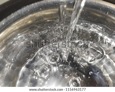 closeup of pouring water into a steel bowl