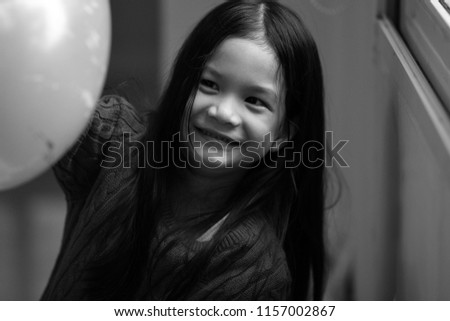 Black and white image of 6 years old Asian girl Blowing balloons.Girl look happy and natural.Concept of Asian  home sweet home.Preteen lifestyle.