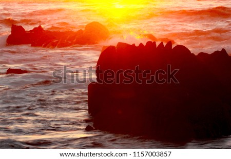 Background of Sunset over Ocean with Silhouetted Rocks and Copy Space