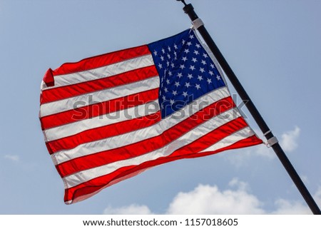 American flag waving on a blue sky with beautiful clouds.