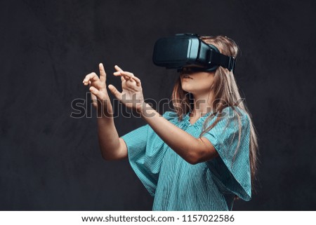 Young girl dressed casual using virtual reality glasses. Isolated on a dark textured background.