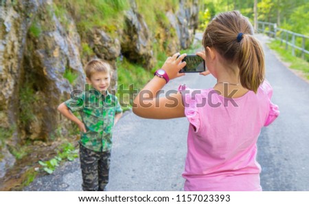little girl takes a picture of her little brother 