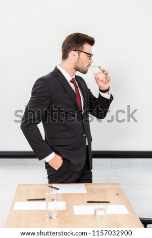 handsome young businessman drinking water at modern office