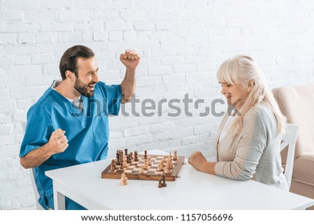 cheerful young man and focused senior woman playing chess together