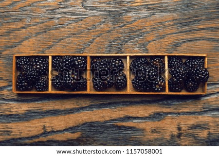 Blackberry berries in portioned trays on a wooden background