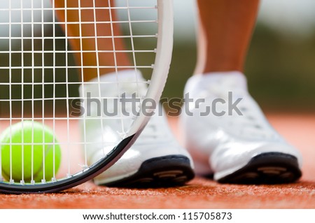 Legs of sportive girl near the tennis racquet and balls