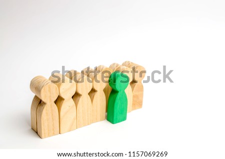 The chosen person among others. A human figure of green color stands out from the crowd. Wooden figures of people. A talented worker, a successful choice. Promotion. Concept of search for worker.