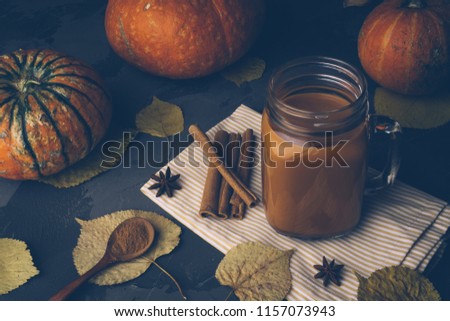 Pumpkin spice chai (masala tea). Autumn, fall or winter hot drink. Background with yellow leaves