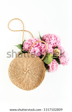 Pink bouquet of hydrangea in a straw bag on white background. Minimal floral concept. Flat lay, top view. 