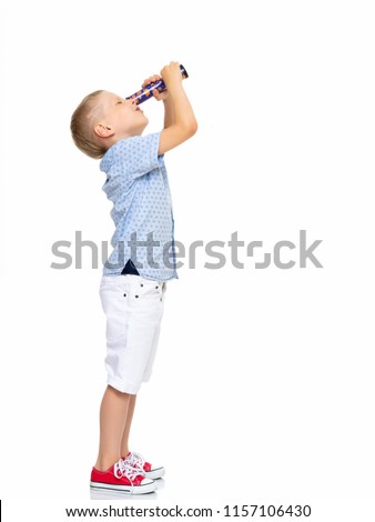 A cute little boy looks through a telescope or kaleidoscope. The concept of studying outer space and the surrounding world, a scientific discovery. Isolated on white background. Royalty-Free Stock Photo #1157106430