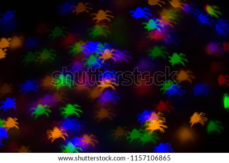 defocused bokeh multicolor lights in shape of spiders for halloween background - holidays, decoration and party concept