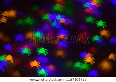 defocused bokeh multicolor lights in shape of spiders for halloween background - holidays, decoration and party concept