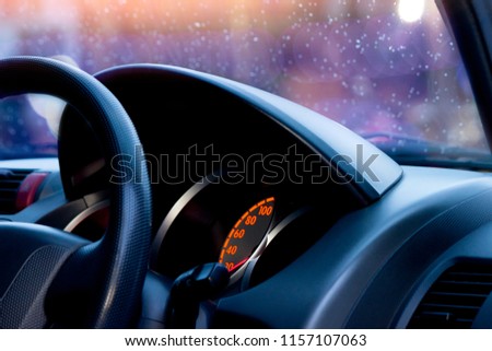 Steering wheel control modern car view inside console on colorful bokeh with drop water of rain on the glass.