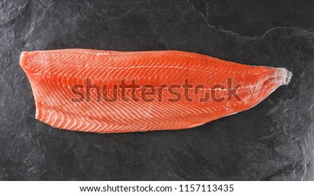 Fresh raw salmon fish steak with spices on ice over dark stone background. Creative layout made of fish, top view, flat lay Royalty-Free Stock Photo #1157113435