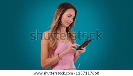 Caucasian woman listening to music and smiling on solid blue background