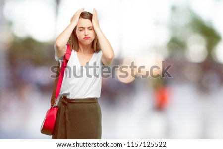 young pretty woman looking stressed and frustrated, with closed eyes and hand on forehead.