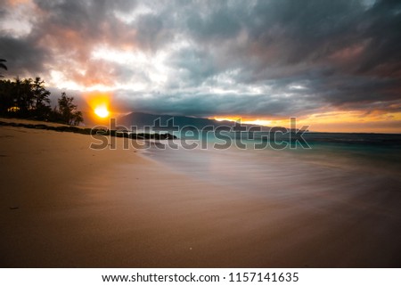 Long Exposure Seascape of Beautiful Sandy Beach with Colorful Sunset and Sun Rays Through Clouds