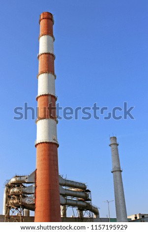 High pipes of industrial enterprise. Plant against the background of a clear sky