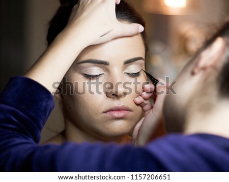 Make up artist doing professional make up of young woman.