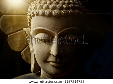 Buddha's head statue carved from sandstone by handmade artisan
who believe strongly and faith in Buddhism with soft light background.
