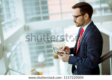 Handsome young man with tablet on stairs in modern office