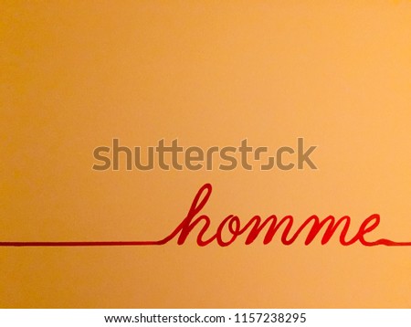 Red cursive handwritten word "Men" in French on a yellow background