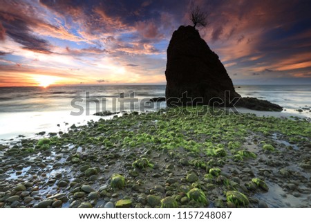 Amazing sunset moment by the beach with green moss covered rocks boulders at Batu Luang, Kuala Penyu, Sabah. (motion blurry soft focus noise visible) Nature composition