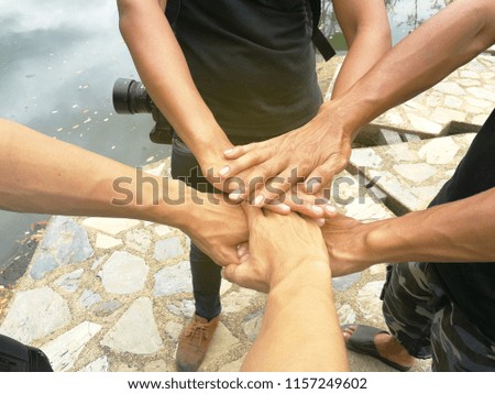 Friends with stack of hands showing unity and teamwork.