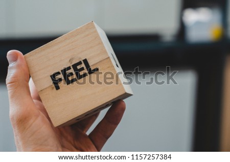 Business and design concept - surreal abstract geometric wooden cube take by hand with word " FEEL " concept in hand and white background