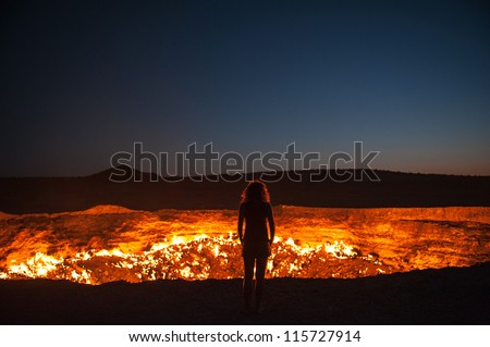 Darvaza, Turkmenistan - Staring into the flaming gas crater known as the Door to Hell In Darvaza, Turkmenistan. Royalty-Free Stock Photo #115727914
