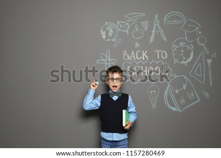 Little child in uniform near drawings with text BACK TO SCHOOL on grey background Royalty-Free Stock Photo #1157280469