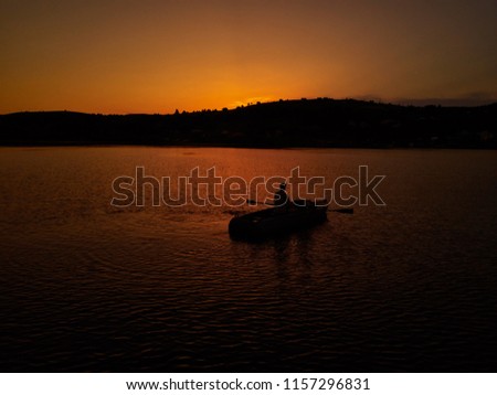 Lonely guy sitting in a boat at sunset. Silhouette