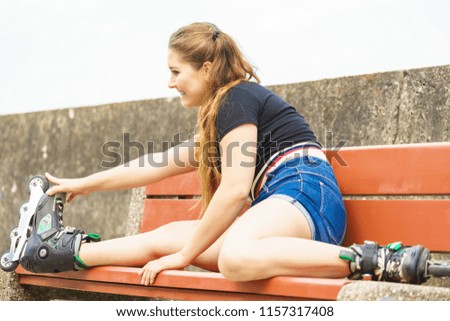 Happy smiling young woman wearing roller skates outdoor. Fashionable fit girl having fun resting on bench.